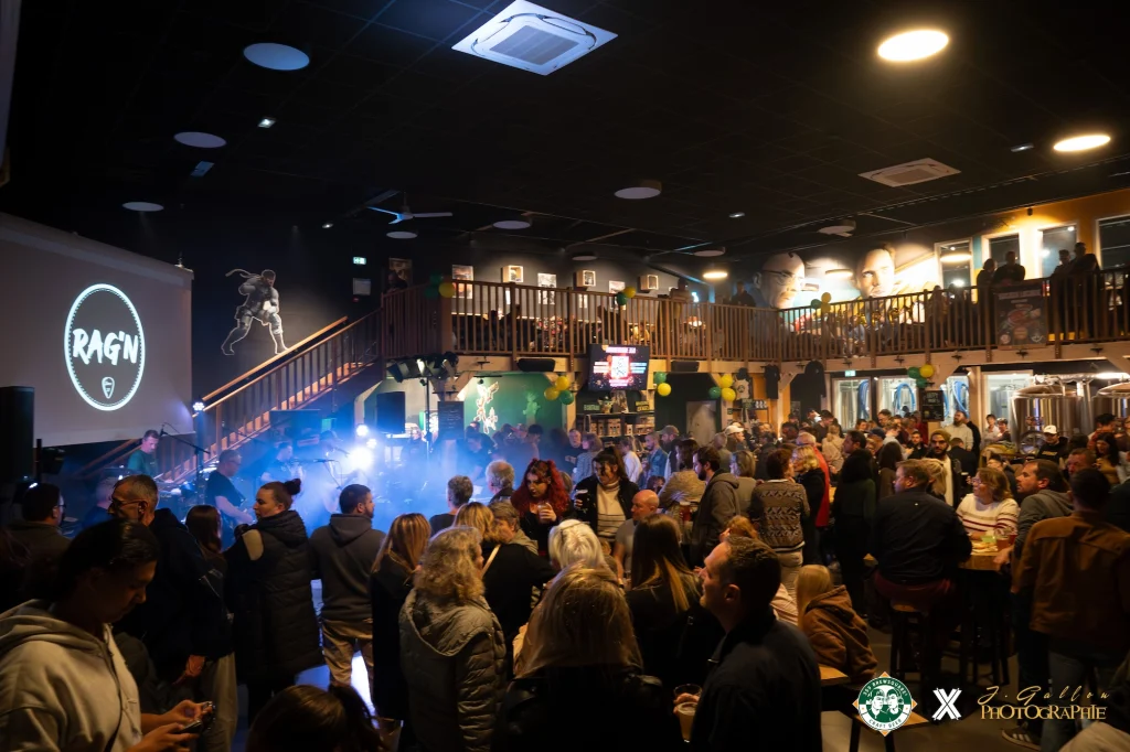 Concert de RAG'N , devant une foule profitant de la musique, de leurs amis et des bières locales.
